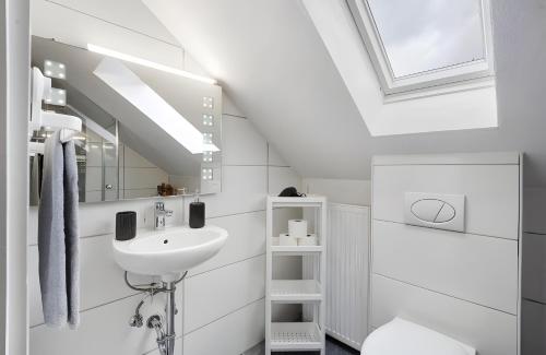a white bathroom with a sink and a skylight at Schwarzwaldglück Loft in St. Blasien