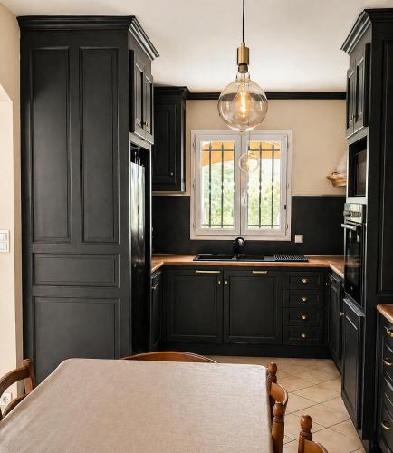 a kitchen with black cabinets and a table and a window at PROVENCE, MAISON SPACIEUSE et CONFORTABLE à coté de SPIROU,NARUTO et , WAVE ISLAND in Monteux