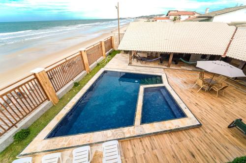 a swimming pool on a deck next to the beach at Luxury Oceanfront House - Beachfront - Pool in Aquiraz