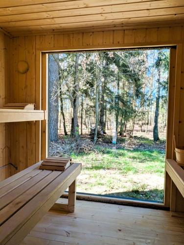 a bench in a wooden room with a large window at Leno Tu - Domki przy jeziorze z sauną i banią in Ciemno