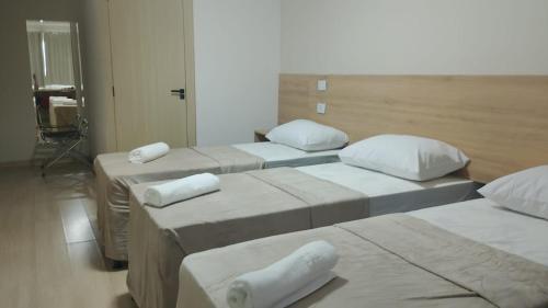 a room with four beds with white pillows on them at Flat 55 Goiania in Goiânia