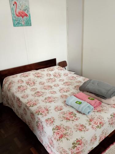 a bed with a floral bedspread and two towels on it at Hostel Uziel in Timbó