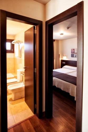 a room with a bathroom with a bed and a mirror at Apartamentos Rurales L'Arquera in Llanes