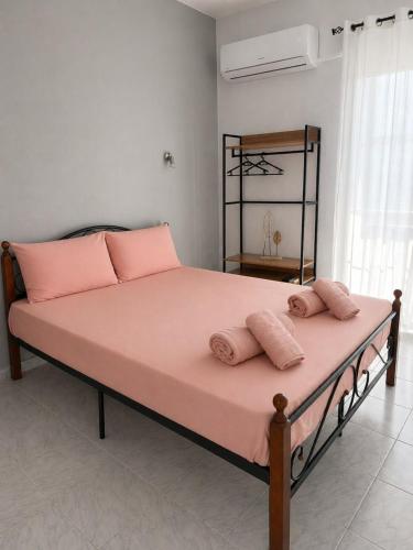 a bedroom with a large bed with pink pillows at Matinas rooms in Nea Mesangala