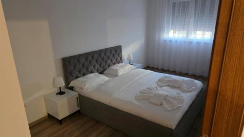 a bedroom with a bed with white sheets and bows at Art Apartment in Prizren
