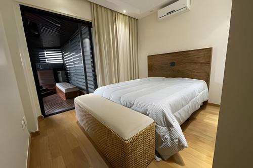 a bedroom with a white bed and a chair at Refúgio Morumbi: Piscina aquecida e espaço gourmet in São Paulo