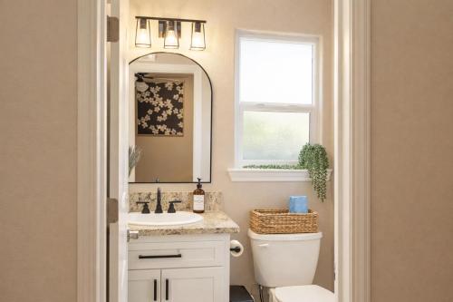 a bathroom with a toilet and a sink and a mirror at Sequoia Oasis near Downtown Exeter in Exeter