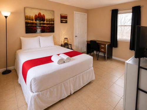a bedroom with a large white bed with towels on it at Skylark Motel by OYO in Bedford