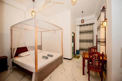 a bedroom with a canopy bed and a chair at Wake N Flow, Hiriketiya Beach in Hiriketiya