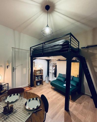 a loft bed in a room with a table and a couch at Chouett'studio in Dijon