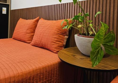 a potted plant sitting on a table next to a bed at IMPERIAL BEACH ENSEADA 500 Metros Praia Enseada Gjá Av Professor João Batista Julião x Antonio Del Nero Enseadas jardim Virgínia Bairro Nobre in Guarujá