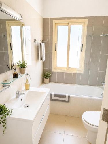 a bathroom with a sink and a tub and a toilet at Stunning Sea View Resort Pools Spa Gym Balcony in Paphos