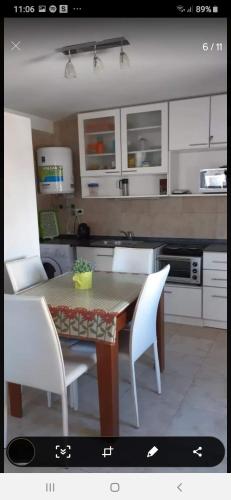 a kitchen with a wooden table and white chairs at Miramar in Miramar