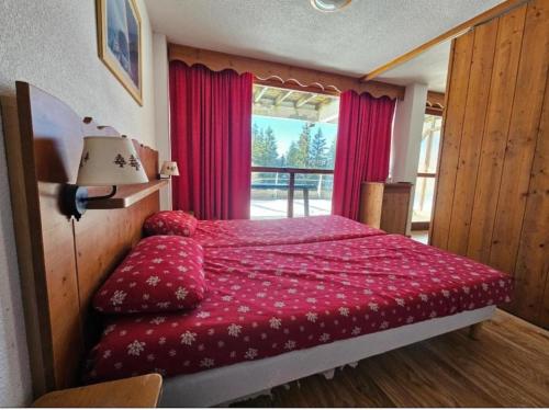 a bedroom with a bed with red sheets and a window at DFJ des Neiges, Piscine, Pieds des pistes in Chamrousse