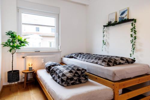 two beds in a room with a window at Living Lu - cosy Apartment three - nähe Mannheim - BASF - Netflix - 3 Zimmer in Ludwigshafen am Rhein