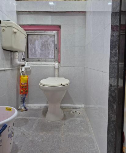 a bathroom with a toilet and a window at Swami Single Bed Dormstay in Ratnagiri
