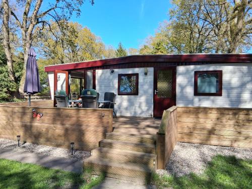 a small cabin with a wooden fence in front of it at Chalet Vuurvos - sfeervol chalet met omheinde tuin, midden in de bossen van Drenthe in Eext