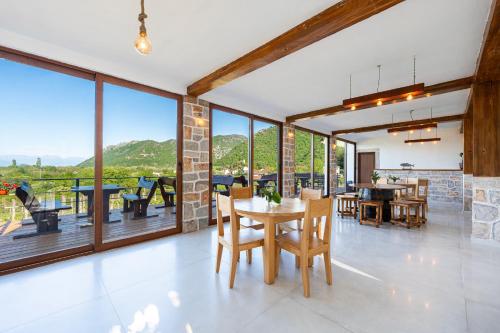 a dining room with a table and chairs and large windows at Vržina Farm House Skadar Lake in Virpazar