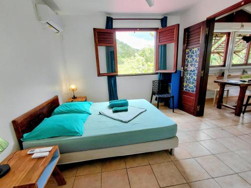 a bedroom with a bed and a desk and a table at GîteTi Coco de Malendure - Bord de mer - 4 pers in Bouillante