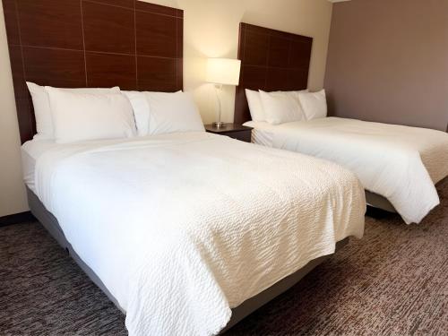 two beds in a hotel room with white sheets at Garner Hotel Pecos by IHG in Pecos