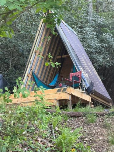 a tent with a chair and a hammock in a forest at The Outside Inn in Cullowhee
