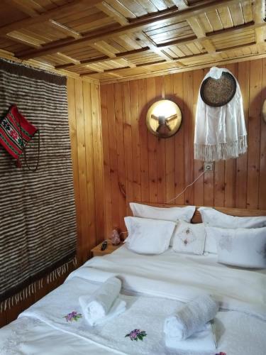 a bedroom with a large white bed with wooden walls at Casa de vacanta 1001 De Nopti in Corbşori