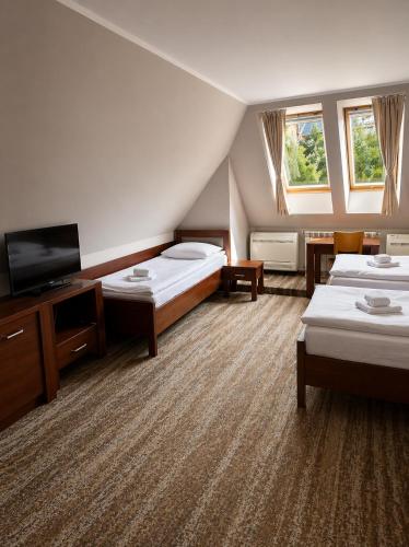 a hotel room with two beds and a flat screen tv at Hotel LOKIS in Niedzica Zamek