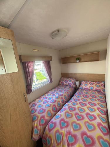 a small bedroom with two beds and a window at S-M Statics in Kinmel Bay