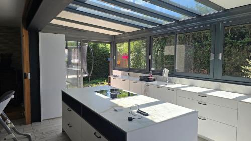 a kitchen with white counters and windows and a sink at Maison de village in Copponex