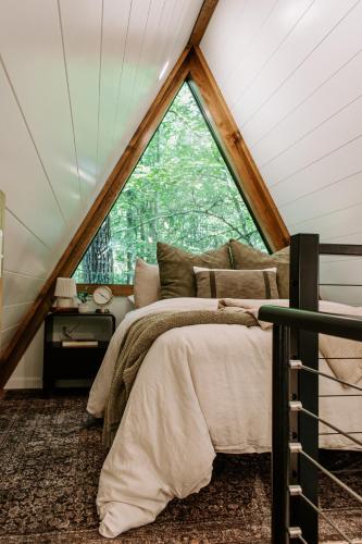 a bedroom with a bed and a large window at Wilewood A-Frame, Romantic Treehouse Getaway, Hot Tub in Abbeville