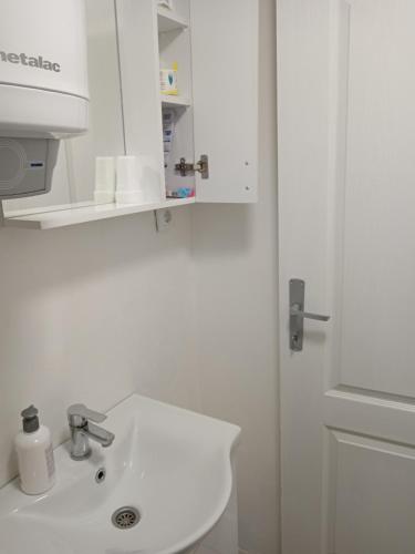 a white bathroom with a sink and a mirror at Tića in Laćarak