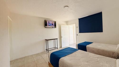 a room with two beds and a tv on the wall at Hotel Plaza del Ángel in Huajuapan de León