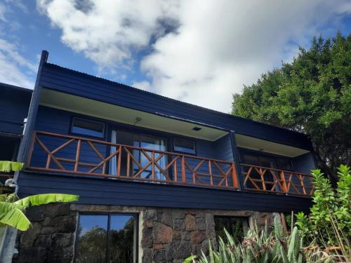 a blue house with a wrap around deck at Hotel Uka Mana in Hanga Roa