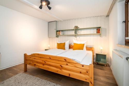 a bedroom with a large wooden bed with yellow pillows at Waterkieker Jabel - Ferienhaus mit Sauna & Steg in Jabel