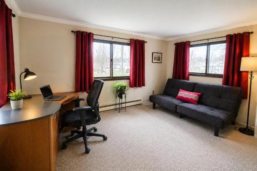 a living room with a couch and a desk with a laptop at Spacious Frontier Park Apartment in Erie