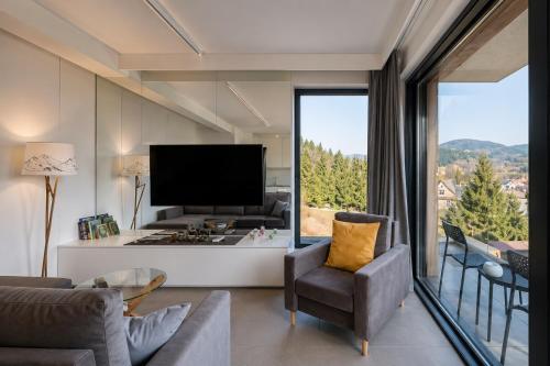 a living room with a couch and a tv and a large window at Kryształ Górski apartament z sauną in Szczyrk