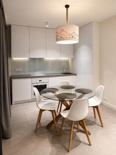 a dining room with a table and white chairs at Kryształ Górski apartament z sauną in Szczyrk
