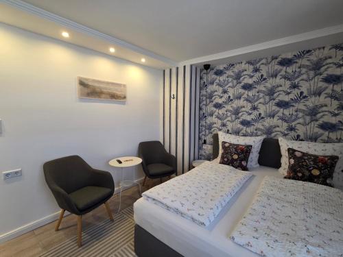 a bedroom with a bed and two chairs at Pension Zur Brandung in Büsum