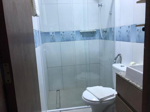 a bathroom with a shower and a toilet and a sink at Apart Hotel Guaiuba in Guarujá