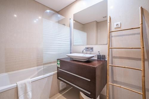 a bathroom with a sink and a shower with a mirror at Living Funchal by Homie in Funchal