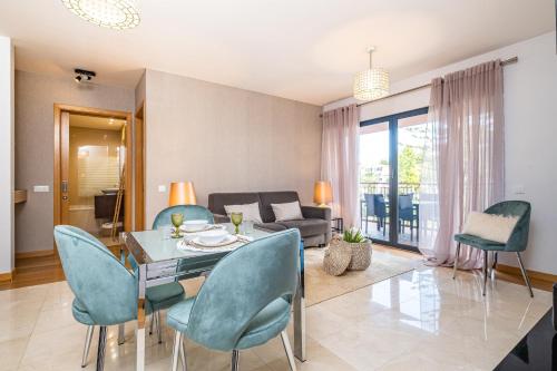 a living room with a glass table and blue chairs at Living Funchal by Homie in Funchal