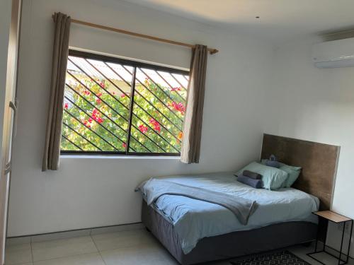 a bedroom with a bed and a window with red flowers at F2 Farmhouse in Omuthiya