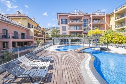 a swimming pool with lounge chairs next to a building at Living Funchal by Homie in Funchal