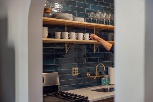 a person reaching for cups on a shelf in a kitchen at The Wilson in Madison