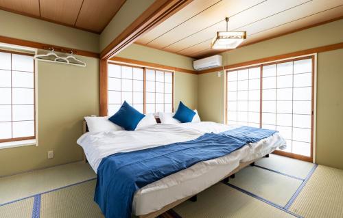 a bedroom with a large bed in a room with windows at Ninja Village - Miyajima in Hatsukaichi