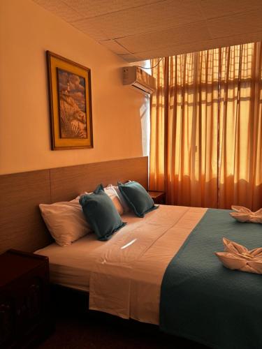 a bedroom with a bed with pillows and a window at Hotel Los Andes Inn in Guayaquil