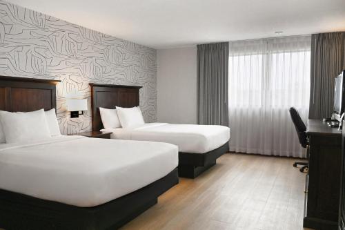 a hotel room with two beds and a television at Clifton Victoria Inn at the Falls in Niagara Falls