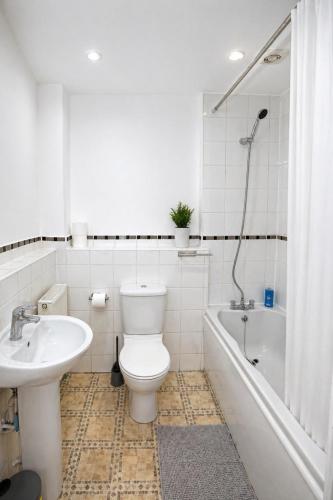 a bathroom with a toilet and a sink and a tub at Greenhithe Guest House in Stonewood