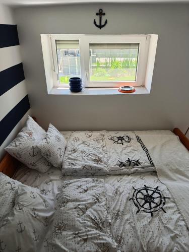a bedroom with a bed with white sheets and a window at Matróz Lak Apartman in Alsóörs