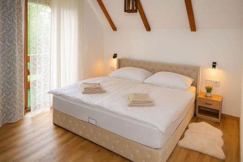 a bedroom with a large white bed with two towels on it at Chalet Wörthersee in Velden am Wörthersee